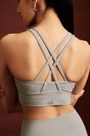 Grey sports bra with a stylish cross-back design for yoga and gym training